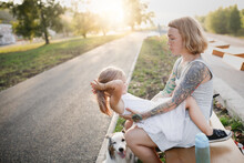 Mother Hugs And Holds Her Daughter In Her Arms, Funny Emotional Mom And Daughter With A Dog. Girl With Hair Upside Down Over Australian Shepherd Dog