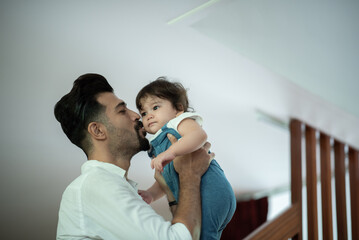 Wall Mural - Cute little toddler baby boy playing and chewing marker pen with father while looking away and thinking at home