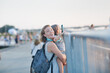 © natalialeb - Mom holds her daughter in her arms looking at the fence at a public event, mom and daughter photo with a smart phone, concert or parade of balloons backpack