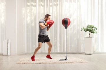 Poster - Boxer with red boxing gloves training with a punch bag in a room