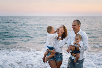 Happy family having fun playing beach in summer vacation on the beach. Happy family and vacations concept. Seascape at sunset with beautiful sky. Family on the beach.