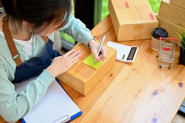 Wall Mural - Overhead shot, Female online shop owner wiring a customer address on a small parcel box