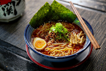 Spicy Sichuan Dandan noodles ramen with chopstick in the traditional Japanese ramen restaurant, with a ramen bowl and Japanese fonts sake barrel translation: Invincible Great Gate