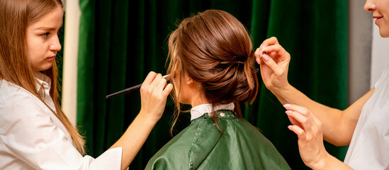 Wall Mural - Makeup artist and hairdresser prepare the bride making hairstyle and makeup in a beauty salon