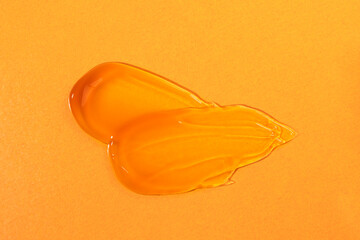 Smears of a cosmetic product in orange color on a bright background top view, flat lay. Body lotion, cleansing mask sample.