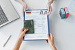 © AnnaStills - Top-down shot of woman applying for travel visa to Germany giving set of documents to consular officer