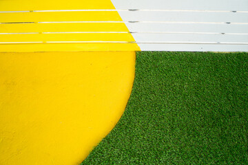 Half circle yellow surface with slat wooden around with artificial grass soccer field, green lawn background.