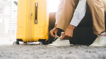 Wall Mural - Asian tourism man hand tying shoelaces for begin a journey travel with luggage