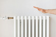 Man holding hand over white heating radiator