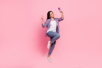 Wall Mural - Full body photo of young brunette lady jump do selfie wear shirt jeans shoes isolated on pink background