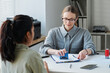 © AnnaStills - Professional consular officer sitting in front of applicant giving approval for travel visa putting seal on document