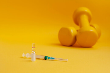 Wall Mural - syringe and a medical ampoule with liquid are standing near dumbbells on a yellow background, copy space. the concept of doping in sports, and other prohibited drugs.