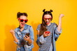 Photo of delighted overjoyed girls blogging raise fist celebrate like subscribe isolated on yellow color background