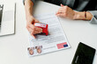© AnnaStills - High angle view of unrecognizable woman working in US embassy rejecting travel visa application putting seal on it