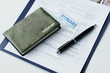 © AnnaStills - High angle close-up of passport in leather cover, travel visa application paper with approved stamp on it and pen on table