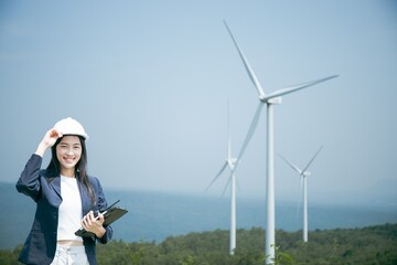 Wall Mural - Project manager beautiful Asian woman raising her arms in joyful. Renewable power plants with hydropower,wind power,wind turbines.Using tablet wearing helmet safety,Formal suit Successful Smiling.