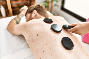 Sticker - Young redhead man having back massage using black stones at beauty center