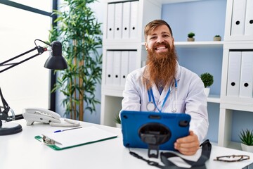 Poster - Young redhead man wearing doctor uniform using touchpad at clinic