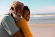 © WavebreakMediaMicro - Side view of happy bearded african american senior man embracing mature woman against sea and sky