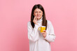 Sick brunette woman suffering from sensitive teeth after drinking hot or cold beverage, cavities, wearing white casual style sweater. Indoor studio shot isolated on pink background.