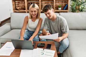 Sticker - Young caucasian couple smiling happy controlling family economy using laptop at home.