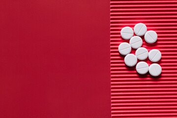 Wall Mural - top view of pile with white round shape pills on crimson textured background.