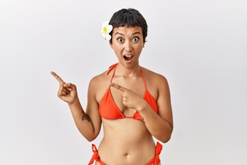 Sticker - Young hispanic woman with short hair wearing bikini pointing aside worried and nervous with both hands, concerned and surprised expression