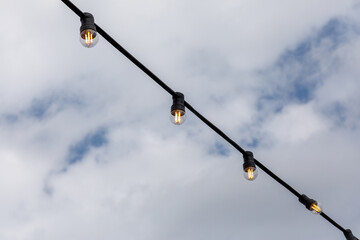 Wall Mural - light bulbs garlands on a background of blue sky 