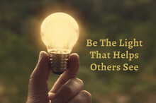 Motivational And Inspirational Quote - Be The Light That Helps Others See. With Light Bulb In Vintage Color Background.