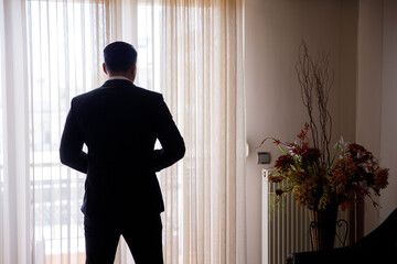 Sticker - Handsome young man standing in front of the window captured from the back