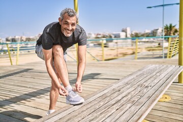 Sticker - Middle age hispanic man smiling confident tying shoe at street