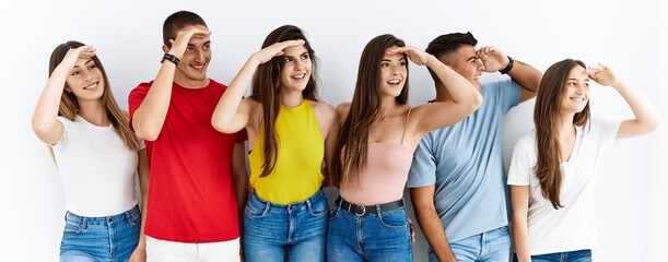 Canvas Print - Group of people wearing casual clothes standing over isolated background very happy and smiling looking far away with hand over head. searching concept.