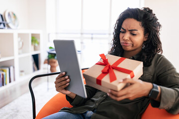 Wall Mural - Unhappy Woman Holding Gift Box In Front Of Tablet