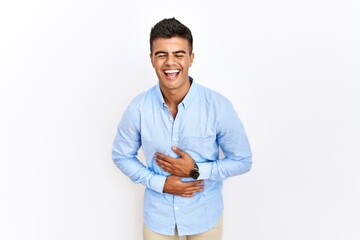 Canvas Print - Young hispanic man wearing business shirt standing over isolated background smiling and laughing hard out loud because funny crazy joke with hands on body.