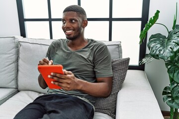 Poster - Young african american man smiling confident using touchpad at home