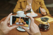 © Mediaphotos - Busy young bearded man sitting at table in modern cafe and drinking coffee while discussing project by phone