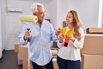 Sticker - Middle age man and woman couple choosing color to paint wall at new home