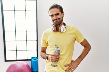 Sticker - Young hispanic man wearing sportswear and drinking water at the gym depressed and worry for distress, crying angry and afraid. sad expression.