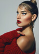 Portrait of a beautiful young tanned woman with a smooth hairstyle and bright red lips. The model poses in a red knitted dress. Advertising of fashionable clothes. Advertisement of decorative cosmetic