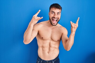 Handsome hispanic man standing shirtless shouting with crazy expression doing rock symbol with hands up. music star. heavy concept.