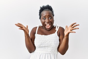 Poster - Young african woman standing over white isolated background celebrating crazy and amazed for success with arms raised and open eyes screaming excited. winner concept