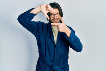 Canvas Print - Middle age caucasian man wearing bathrobe and glasses smiling making frame with hands and fingers with happy face. creativity and photography concept.