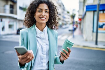 Wall Mural - Young hispanic business woman wearing professional look smiling confident at the city using smartphone