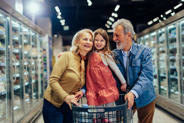 Wall Mural - Grandparents and girl shopping in modern supermarket