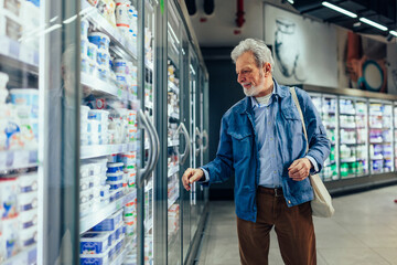 Senior man at supermarket buying milk products