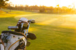 Golf clubs in bag on grassy landscape against clear sky at golf course during sunset, copy space