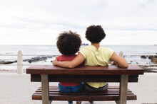Rear View Of Afro African American Young Couple Looking At Sea While Sitting Together On Bench