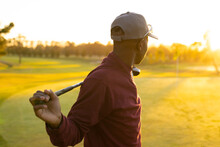 Side View Of African American Young Man Wearing Cap Holding Golf Club While Standing At Golf Course