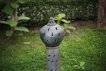 Poster - Closeup shot of a silver metal plate torch in the garden during daytime with blurred background