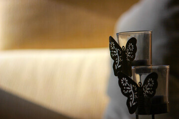 Poster - Two glass candlesticks with decorative black butterflies on a blurry background